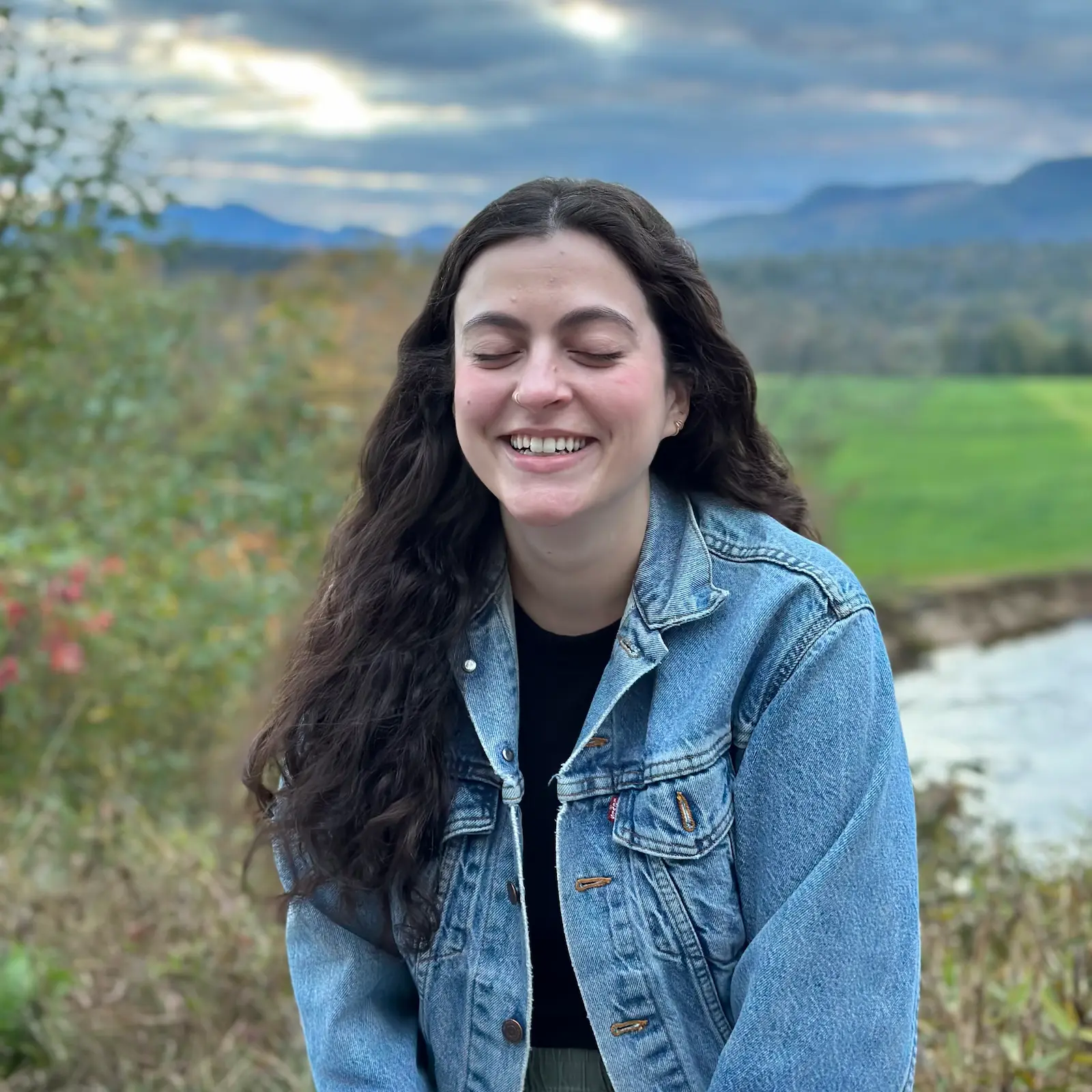 Asha with her eyes closed smiling at a scenic overlook on the White Mountain Highway in North Conway, New Hampshire.