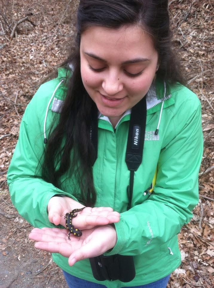 Asha in a green raincoat holding a yellow spotted salamander somewhere in Rhode Island.